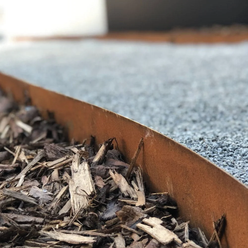 Core-ten weathered steel edging with bark chippings Core-ten weathered steel metal edging with bark chippings