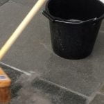 Bucket of water and broom sweeping patio